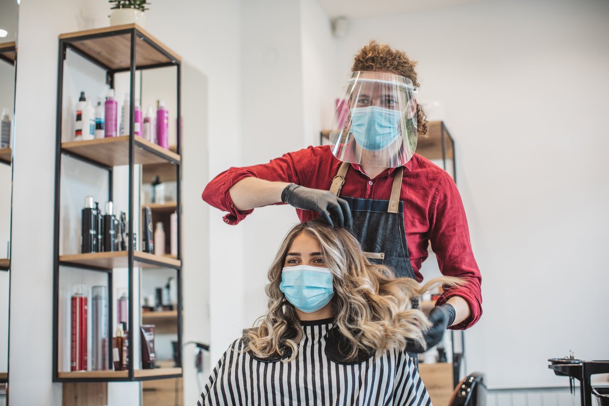 woman getting a hair cut at the hairdressers during a pandemic wearing face masks